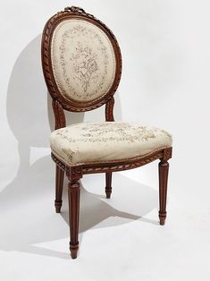 an antique chair with white upholstered fabric on the seat and back, against a white background