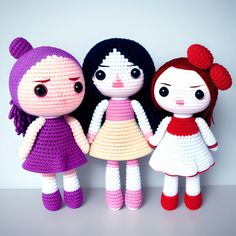 three crocheted dolls standing next to each other in front of a white wall