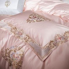 the comforter is pink with gold trimmings and decorative designs on it's edges