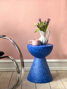 a blue vase with flowers sitting on top of a table next to a wheel chair