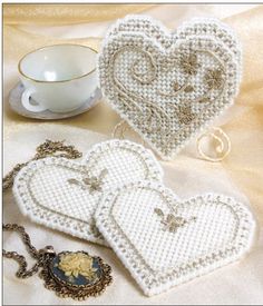 two white heart shaped purses sitting on top of a table next to a cup and saucer