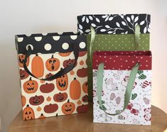 two bags with pumpkins on them sitting on a table next to another bag that has polka dots