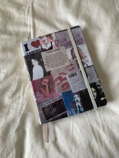 an open notebook with pictures and words on it sitting on a bed sheet covered in white sheets