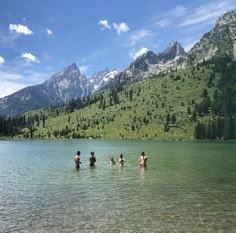 several people are wading in the water near mountains