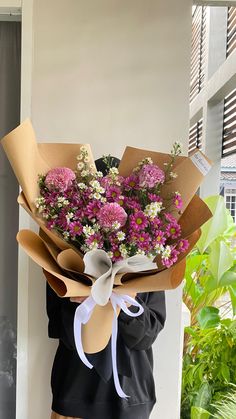 a woman holding a bouquet of flowers in her hands while standing next to a building