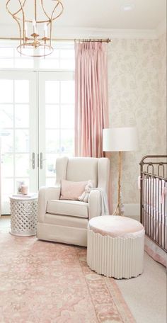 a baby's room with pink and white decor, including a crib, rocking chair, lamp, and chandelier