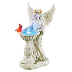 an angel statue sitting on top of a fountain with a red bird perched on it