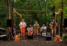 a group of people that are standing in the dirt with guitars and singing into microphones