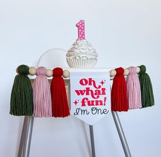 a cupcake on top of a cake stand with tassels hanging from it