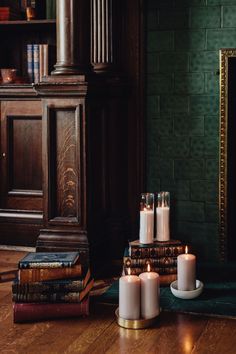 candles and books on the floor in front of a fireplace