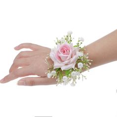 a woman's hand holding a pink rose and white baby's breath wrist corsage