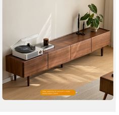 a record player sitting on top of a wooden table next to a potted plant