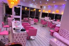 a salon with pink chairs and chandeliers on the ceiling is lit by lights