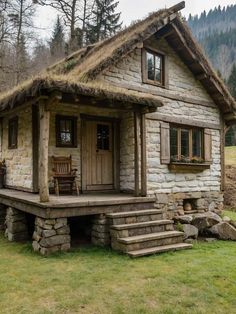 a small stone house with grass roof and steps leading up to the front porch area