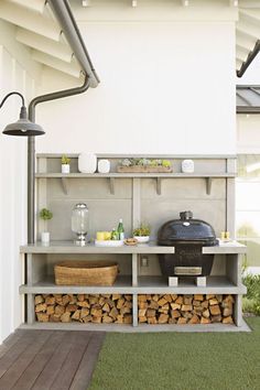 an outdoor bbq with lots of wood stacked on the shelves and grilling area