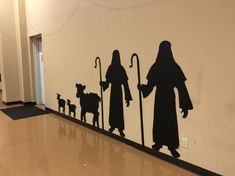 the silhouettes of three people and two dogs are painted on a wall in a hallway