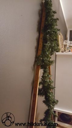 a wooden ladder with plants growing on it next to a white cabinet and window sill