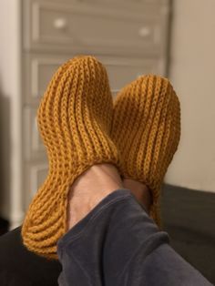 a person's feet wearing knitted yellow mittens