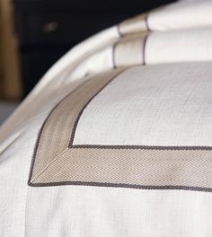 a close up view of a bed with white and brown sheets