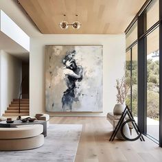 a large painting hangs in the middle of a living room with modern furniture and artwork on the walls