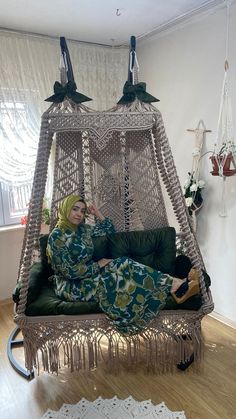 a woman laying in a hammock chair with two birds hanging from the ceiling