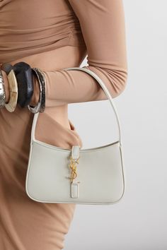 SAINT LAURENT's shoulder bag has a sleek, minimal silhouette that calls to mind coveted '90s styles. Made in Italy from off-white leather, it's adorned with the house's signature 'YSL' plaque and has plenty of space for your phone, keys and cardholder. White Ysl Bag, White Handbag Outfit, White Purse Outfit, Ysl Bag Outfit, White Hand Bag, Small Designer Bags, Saint Laurent Tote, Purse Outfit, Sacs Tote Bags