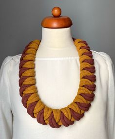 a woman wearing a yellow and brown necklace on top of a mannequin head