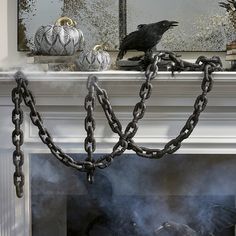 a black bird sitting on top of a fire place with chains hanging from it's sides