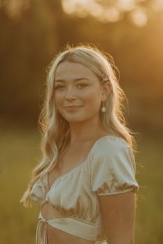 a woman in a white dress is posing for a photo with the sun behind her