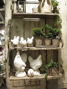 an old wooden shelf filled with potted plants and chicken figurines