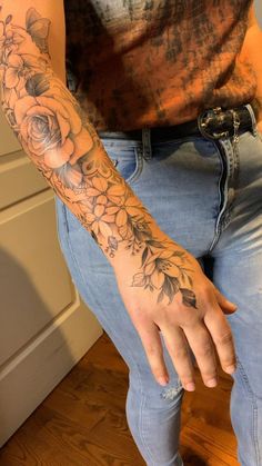 a man with a flower tattoo on his arm and hand is sitting in front of the camera