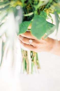 a close up of a person holding a bouquet of flowers with a ring on it