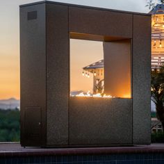 an outdoor fire pit in the middle of a swimming pool at night with lights on it