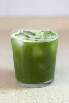 a glass filled with green liquid on top of a table