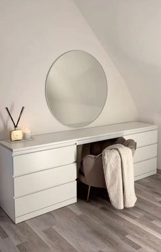 a white dresser with a round mirror above it