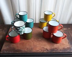 there are many cups on the table with one cup in the middle and four mugs out front