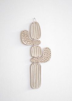 three ceramic cactus ornaments hanging on the wall, one is made from wood and the other has