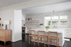 a kitchen with white cabinets and wooden stools