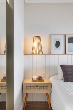 a white bed sitting next to two framed pictures on the side of a wall in a bedroom