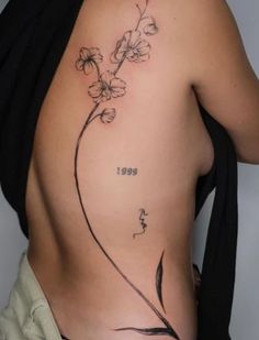 a woman's back with flowers and numbers tattooed on her lower side ribcage