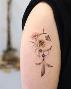 a woman's arm with a tattoo on it that has flowers and a crescent