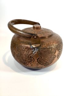 a metal teapot with a wooden handle on a white surface in front of a white background