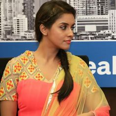 a woman sitting in front of a sign with her hand on her hip and wearing a sari