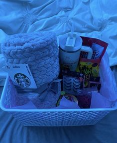 a basket filled with items on top of a white bed next to a blue comforter