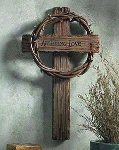 a wooden cross with the words amazing love on it next to a potted plant