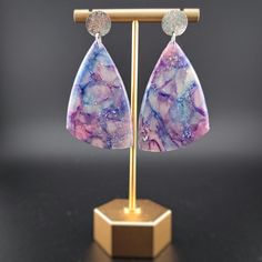 These translucent earrings are beautiful in any light, but they absolutely stun when graced by the sun. Threads of lavender, turquoise, and magenta dance through each piece. They are a great gift for anyone wanting to embrace their whimsical side with a touch of elegance! They are handmade and unique--no two have the same design. They are lightweight, which makes them a thoughtful gift for anyone who has trouble with heavier earrings. Each earring is made by hand and will have slight variations in the pattern. All of my materials are nickel-free and hypoallergenic. Reika means "wander" in Icelandic, and being a wanderer is crucial to my existence. As such, all of my pieces are imbued with parts of the natural world that have inspired me. It is my hope to provide this same inspiration to an Iridescent Bohemian Earrings, Hypoallergenic Purple Bohemian Earrings, Iridescent Bohemian Earrings For Gifts, Iridescent Bohemian Earrings As Gift, Unique Purple Earrings With Ear Wire, Handmade Purple Drop Clip-on Earrings, Purple Resin Earrings As A Gift, Purple Resin Earrings For Gift, Purple Resin Earrings As Gift