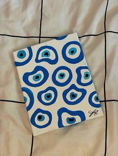 a blue and white square with an eye pattern on it sitting on a bed sheet