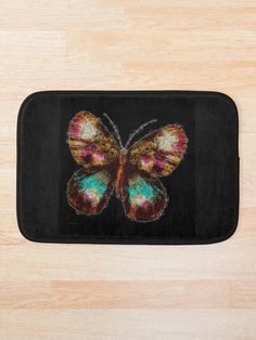 a bath mat with a colorful butterfly on the front and back of it, sitting on top of a wooden floor