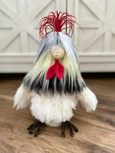 a white and black bird with red feathers on it's head sitting on a wooden floor