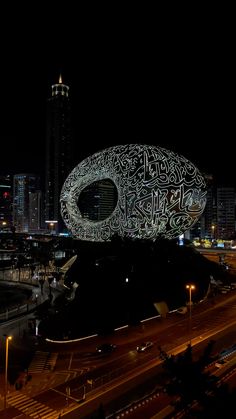 a large white object in the middle of a city at night with lights on it